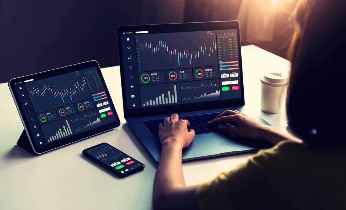 freepik-businesswoman-trader-looking-on-laptop-and-tablet-smartphone-with-graphs-analysis-candle-line-in-office-room